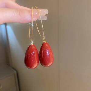 Gros plan de boucles d'oreilles gouttes rouges avec crochets dorés et effet de brillance