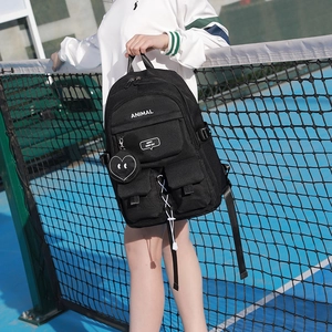 Black nylon backpack with pockets and heart charm shown on a blue tennis court