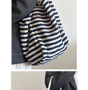 Macro detail of blue striped canvas tote bag with red embroidery and woven texture