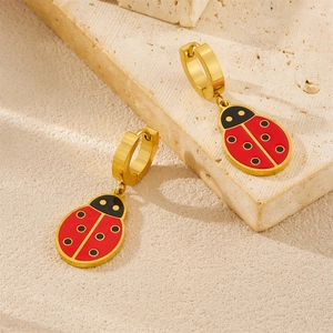Gold-plated ladybug huggie hoop earrings with red enamel on a textured stone base