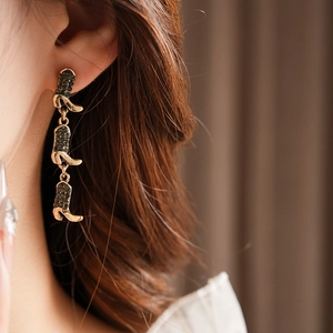 Detail of golden boot tassel earrings with black rhinestones on a female model