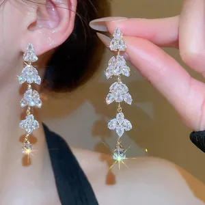 Elegant gold leaf fringe tassel earrings with sparkling rhinestones worn on ear
