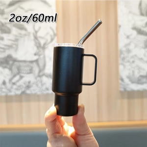 Macro close-up of a 2oz black mini tumbler with handle and metal straw in hand