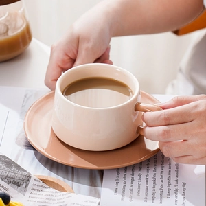 Nordic ceramic coffee cup and saucer set in beige and terracotta on a sunlit table