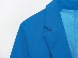 Détail d'un blazer bleu vif montrant la texture du tissu, le revers et l'épaule