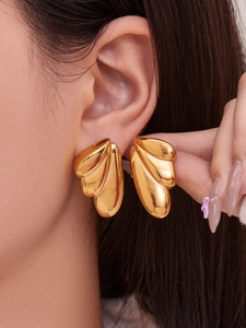 Detailed view of polished 18k gold-plated angel wing earrings on a model’s ear