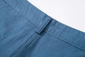 Detailed macro view of heavy-duty cotton canvas waist loops and double stitching on blue shorts