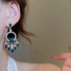 Dettaglio di orecchini in argento con farfalla e nappe verde smeraldo indossati da modella