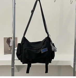 Close-up of black canvas messenger bag with adjustable strap and blue label detail