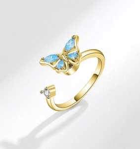 Close-up of golden butterfly open ring with blue marquise crystals and clear zircon
