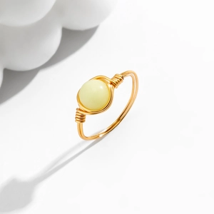 Detailed macro view of handmade gold wire-wrapped ring with a creamy opal gemstone