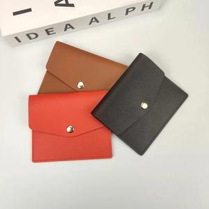 Flat lay of slim envelope card holders in orange, tan, and dark brown with gold button snap