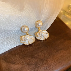 Detailed view of elegant camellia earrings with cream pearls and gold petals
