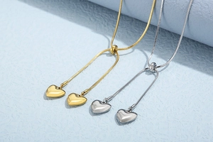 Macro detail of gold and silver heart pendants on adjustable snake chain necklaces