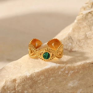 Detailed macro view of an 18K gold-plated eye ring with a green natural stone on a rock