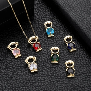 Golden boy shaped pendants with colorful zircon stones on black leather background