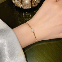 Elegante pulsera de cadena dorada con una perla redonda blanca traslúcida en la muñeca
