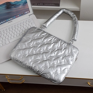 Quilted silver laptop sleeve with bow patterns on a desk with a MacBook Air