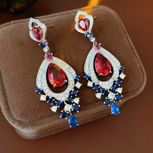 Detailed close-up of vintage teardrop earrings with red and blue zircon on velvet