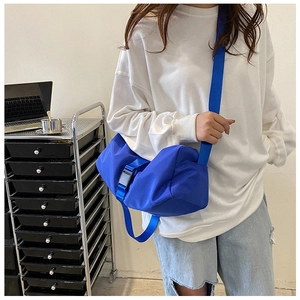 Close-up of bright blue oxford crossbody bag with adjustable black buckle on shoulder strap