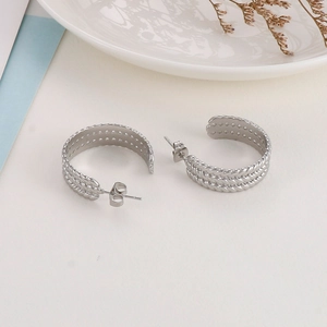 Detailed view of silver-plated twisted rope hoop earrings on a minimalist white tray