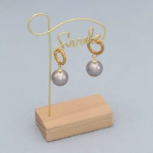 Close-up of elegant grey pearl earrings hanging on a minimalist golden metal stand