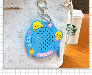 Close-up of the blue magnetic duck drawing board keychain attached to a textured white bag