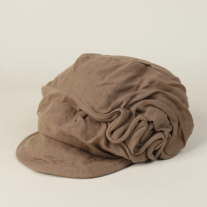 Detail of deep brown linen newsboy cap showing textured pleated fabric and short curved brim