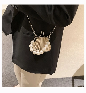 Detail einer Mini-Muschel-Umhängetasche aus Metall mit weißen Perlen und Perlenkette