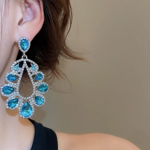 Detailed close-up of luxury pear-shaped sea blue crystal drop earrings with silver accents