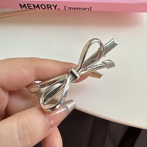 Detailed view of a polished silver metal bow hair clip with a stylish minimalist design
