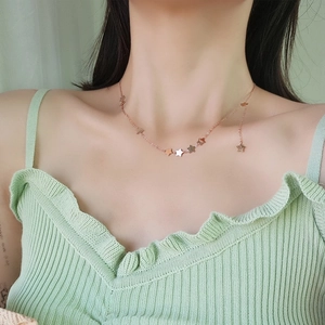 Macro shot of rose gold star necklace charms on a model for a stylish elegant look