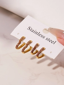 Detailed macro of C-shaped earrings with pink gradient zircons on golden stainless steel