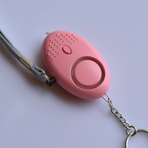 Detail of pink egg-shaped personal security alarm with lanyard and metal keychain