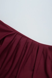 Detail view of the elegant wine red pleated fabric with subtle glossy finish on the dress