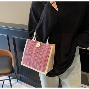 Detail of pink striped linen tote bag featuring a large button closure and woven handles