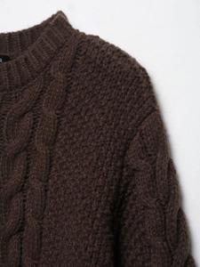 Close-up of dark brown cable-knit texture and thick woven pattern on retro sweater