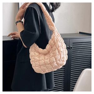 Close-up of lightweight light pink quilted puff cloud bag worn as a crossbody by model