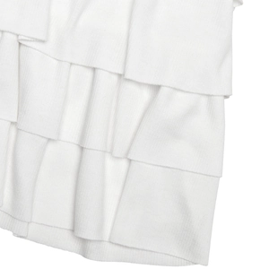 Detailed close-up of white ribbed knit fabric with elegant layered ruffle design