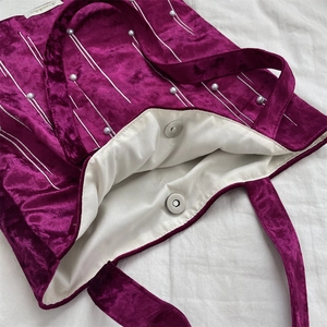 Close-up of velvet tote bag featuring pearl embellishments and magnetic clasp detail