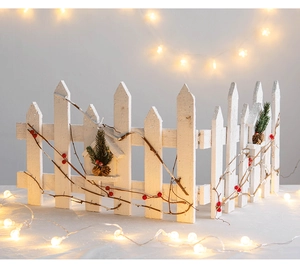 Detailed view of white wooden Christmas fence decorated with pine cones and berries