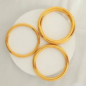 Three classic 18K gold plated minimalist round bangles on a white stone tray