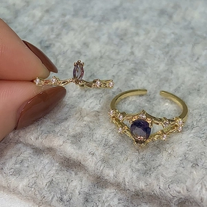 Detail of vintage gold crown ring with purple drop zircon and V-shaped crystal band
