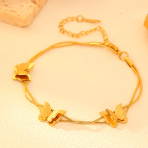 Macro detail of a 18k gold plated double layer snake chain bracelet with butterfly charms