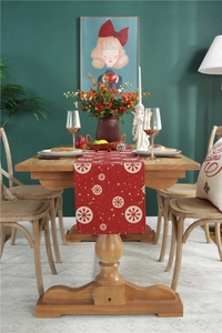 Close-up of red Christmas table runner with white snowflake patterns on linen fabric