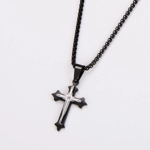 Close-up of black metal cross pendant with silver detail and small diamond on chain