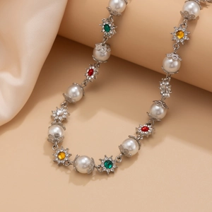 Détail du collier de perles avec des breloques fleurs aux pierres colorées sur soie