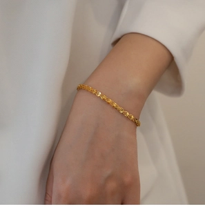 Dettaglio di un bracciale vintage in oro al polso di una donna con finitura lucida 18K