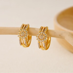 Macro detail of gold-plated flower earrings with shimmering cubic zirconia inlay