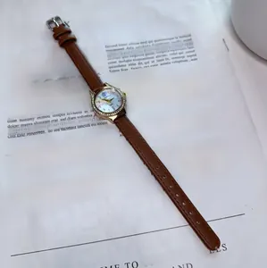 Detail view of quartz watch with brown leather strap and crystal bezel on magazine